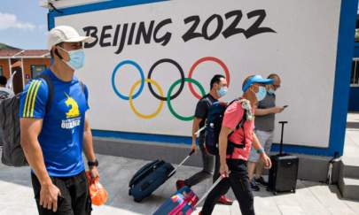 Visitors to Chongli, one of the venues for the Beijing 2022 Winter Olympics, pass by the Olympics logo in Chongli in Hebei Province, China, on Aug. 13, 2020. (Ng Han Guan/AP Photo)