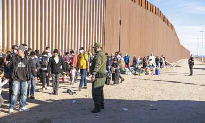  Border Patrol agent organizes illegal immigrants who have gathered by the border fence after crossing from Mexico into the United States in Yuma, Arizona, on Dec. 10 2021. (Charlotte Cuthbertson/The Epoch Times)