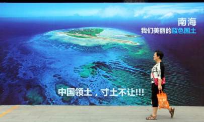 A woman walking past a poster of the South China Sea, with the slogan at the bottom "China's territory, never to yield an inch of our ground" on a street in Weifang, east China's Shandong Province, on July 14, 2016. (STR/AFP/Getty Images)