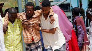 AP - FILE - Somalis help a civilian who was wounded in suicide bomb attack at a military base in Mogadishu, Somalia, June, 15, 2021