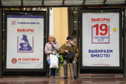 FILE - In this Sept. 8, 2021, file photo, people sit at a bus stop decorated with posters ahead of the election to the State Duma, the lower house of parliament, and the local legislature in St. Petersburg, Russia. There will be three days of voting this weekend, ending on Sunday, Sept. 19, for the new parliament that is unlikely to change the country’s political complexion. (AP Photo/Dmitri Lovetsky, File) 