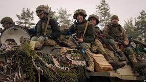 AP - Ukrainian servicemen ride on an armored transporter moving through a Russian position that had been overrun by Ukrainian forces outside Kyiv, Ukraine, March 31, 2022.